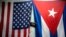 Banderas de Estados Unidos y Cuba cuelgan de una pared con una vieja cámara fotográfica colgada en el medio en La Habana, Cuba, el lunes 11 de enero de 2021. (Foto AP/Ramón Espinosa)