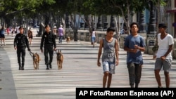 La gente camina en el Paseo del Prado mientras miembros de la policía patrullan en La Habana, Cuba, el lunes 11 de julio de 2022.