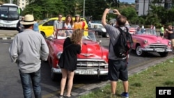 Turistas en La Habana se toman fotos sobre un "almendrón" americano de los años 50.