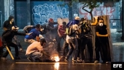 Un grupo de manifestantes opositores al gobierno de Nicolás Maduro se enfrenta a miembros de la Policía Nacional Bolivariana (PNB).