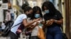 Cubanas usando el celular en las calles de La Habana. (Photo by YAMIL LAGE / AFP).
