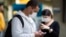 Pasajeros usando mascarillas como precaución contra el contagio del nuevo coronavirus usan sus teléfonos en el Aeropuerto Internacional de Sao Paulo, Brasil.
