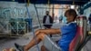 Un taxista en bicicleta espera clientes afuera de una vivienda, en La Habana, donde la policía controla el acceso a un vecindario. (AP/Ramon Espinosa)