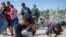 Una familia de inmigrantes después de romper una barricada de alambre de púas hacia los Estados Unidos, después de horas de espera en el Río Grande, en Eagle Pass, Texas, el 25 de septiembre de 2023. ANDREW CABALLERO-REYNOLDS / AFP.
