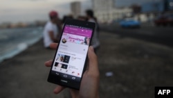 Un youtuber cubano muestra su canal en un teléfono móvil en el Malecón habanero.