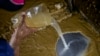 Un trabajador mexcla agua con oro y mercurio en una hoja de aluminio en una mina de oro de El Callao.
