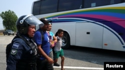 Una familia de migrantes centroamericanos es detenida por un policía federal en Mapastepec, México.