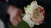 Una mujer sostiene una rosa ensangrentada en protesta contra los feminicidios.