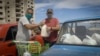 Dos hombres acomodan la mercancía adquirida en una de las tiendas en dólares abiertas la semana pasada en Cuba. (Adalberto Roque / AFP)